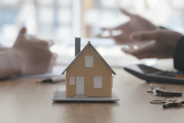 Close up house model on blur background of real estate agent and customer